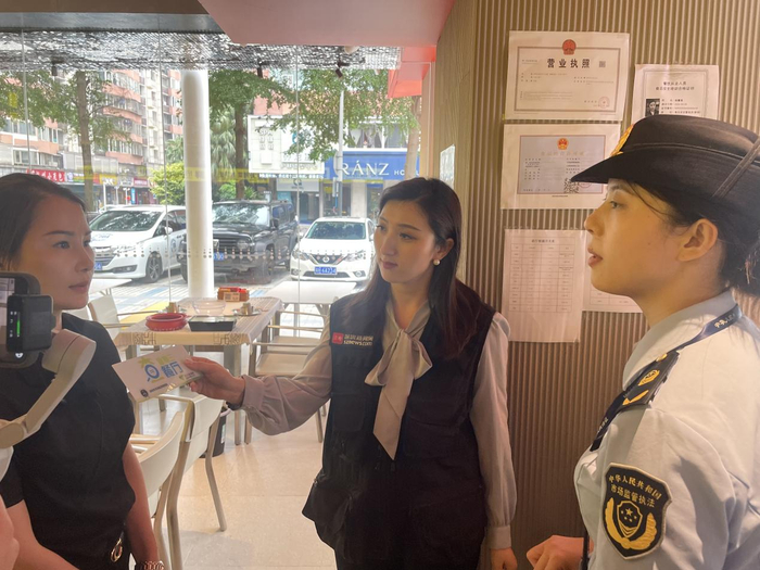 执法人员检查证照公示情况，餐厅负责人答执法人员提问。