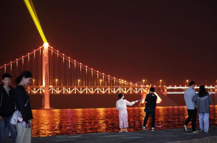 2024年5月23日，在辽宁省大连市，游客在观赏星海湾大桥的光影秀。新华社记者 李钢 摄