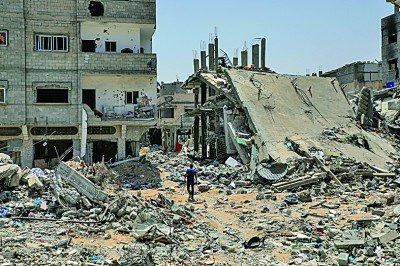     5月21日，在加沙地带南部城市汗尤尼斯，巴勒斯坦人经过以军轰炸后的废墟。新华社发