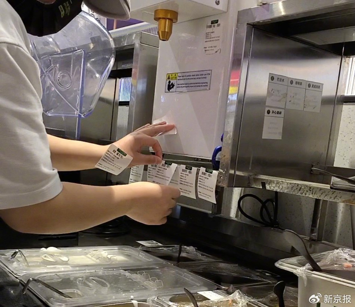 4月28日14时许，茉酸奶石景山万达店店员更换效期标签，为过期食材“续命”。 新京报记者 丛之翔 摄