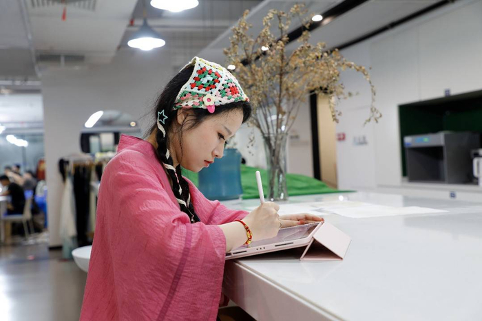 ▲蔡晓彤正在为新中式服饰画设计草图。 陈财|摄
