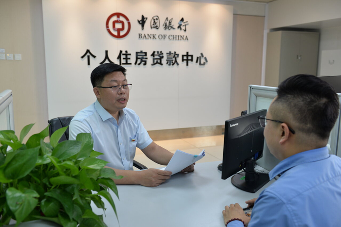 5月27日，中国银行石家庄平安支行个人住房贷款中心主管左继革（左）向客户介绍住房贷款业务。王婧涵 摄