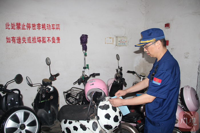 消防检查人员对违规停放的电动自行车张贴安全提醒。