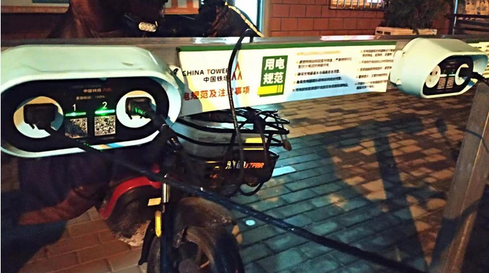 铁塔充电充电桩上正在雨中充电的电动自行车。杜科/摄