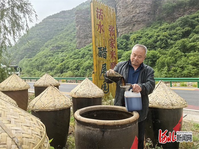 5月24日，张海良将晒好的老陈醋分装到塑料桶里。 河北日报记者 周聪聪摄