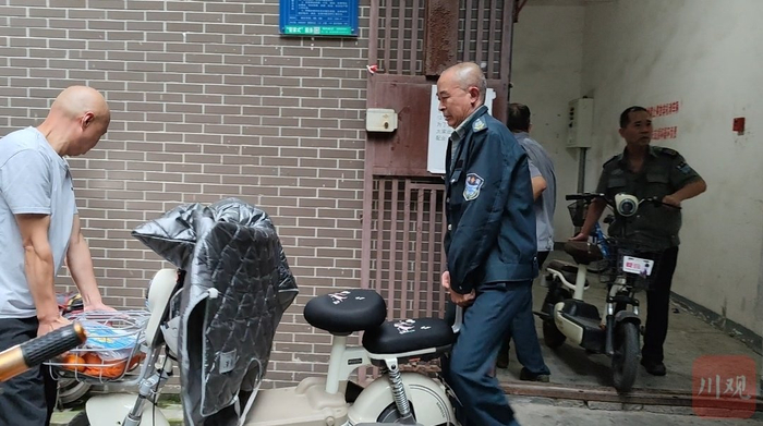 旌南小区物业工作人员对违规停放的电动自行车进行清理。