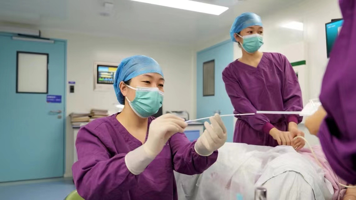 2024年5月，南宁市第二人民医院生殖医疗中心主任李荣（左一）在手术间为患者进行胚胎移植手术。（受访对象供图 ）