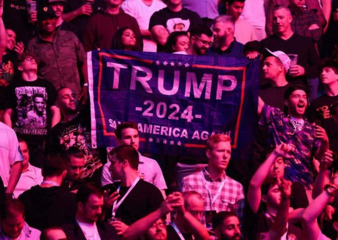 当地时间6月1日，特朗普出现在新泽西州纽瓦克的终极格斗冠军赛现场，他的支持者在观众席举起横幅表示欢迎。图源：法新社