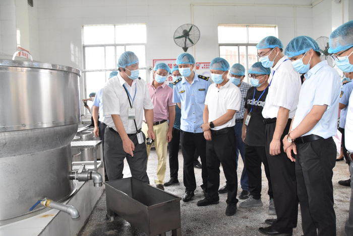 容县中学食品安全总监向参会人员介绍蒸饭间如何在洗米中防止淘米水积留地面。广西容县市场监管局供图