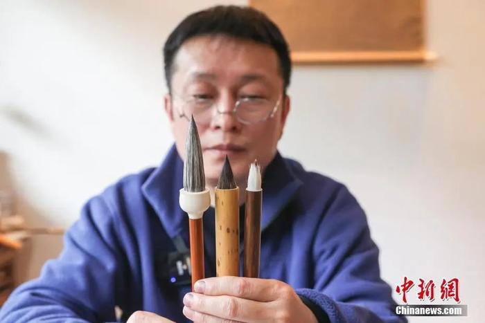 　　李小平展示自己新研发制作的李家笔样、复刻的“唐代缠纸笔”原型、仿“唐代缠纸笔”三支毛笔。刘力鑫 摄