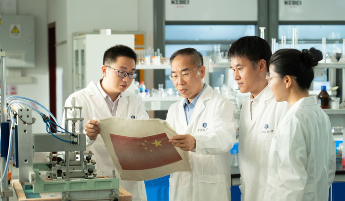 （徐卫林院士（左二）和月面国旗团队教师曹根阳、王运利、盛丹研讨国旗研制技术问题）