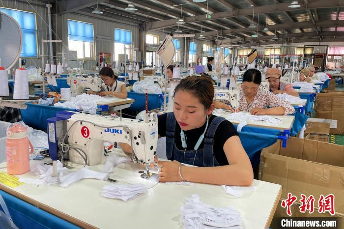 欣荣村移民妇女在村里的制衣扶贫车间内就近务工。中新网记者 李佩珊 摄