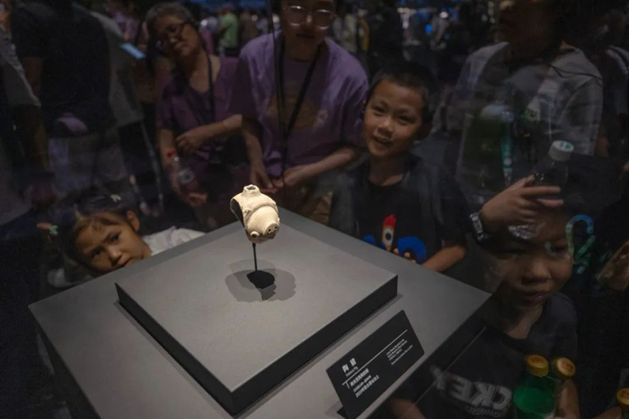 ▲6月1日，游客们在三星堆博物馆陶猪文物前驻足围观。