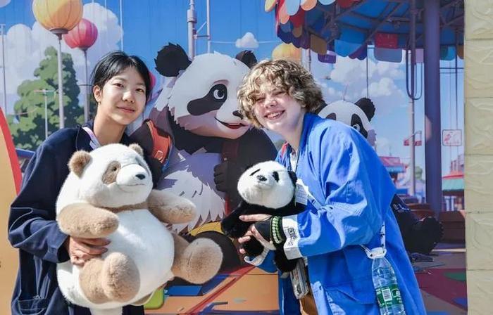 4月21日，中美学生在石家庄动物园大熊猫馆内手持熊猫玩偶留影。
