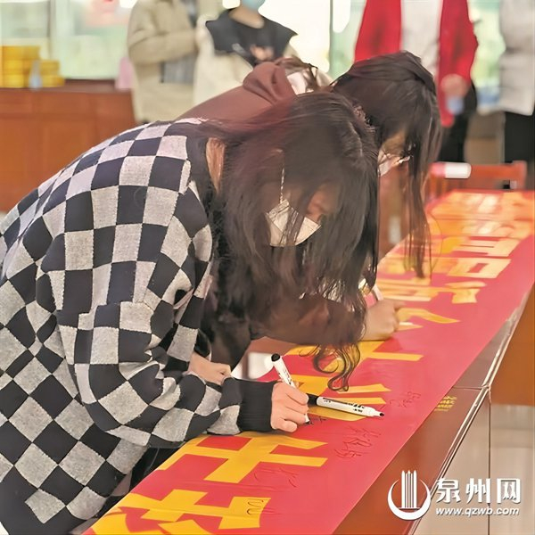 大学生在抵制天价彩礼、推动移风易俗宣传横幅上签名。