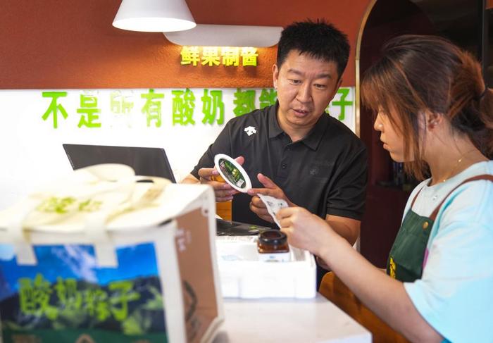   在乌鲁木齐，博斯坎酸奶粽子品牌创始人张磊（左）在门店与工作人员沟通如何搭配礼盒内容。