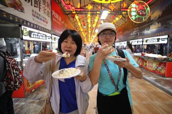 来自辽宁的游客在和田夜市品尝酸奶粽子。