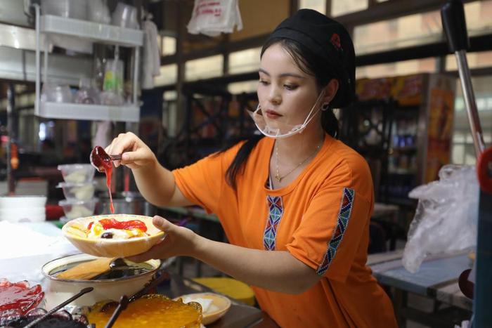   麦斯图热姆在和田夜市为顾客制作酸奶粽子。