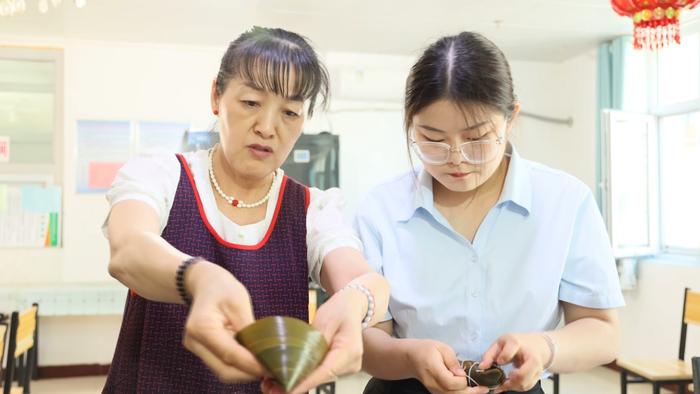 七师胡杨河市开展端午节慰问活动，职工群众来到苏兴滩托老护理院为老人包粽子。