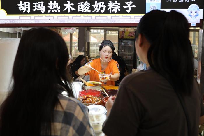   人们在位于和田市的和田夜市上选购粽子。
