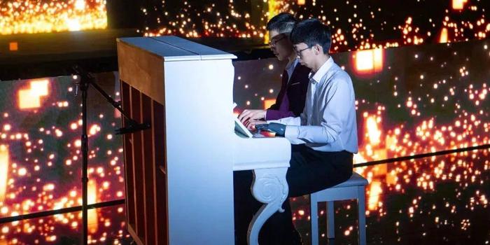 古月在“智融未来”·AI成果展示会上与来自星星的钢琴少年舒海峰四手联弹