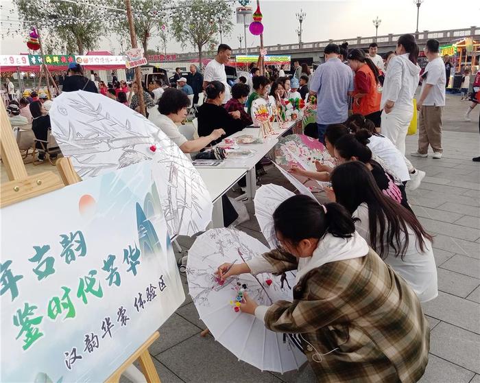 　　兴安盟科右前旗兴安北京社区石榴籽邻里文化大集上，居民正在汉韵华裳体验区描绘油纸伞。