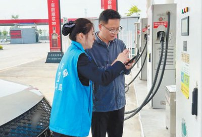 　　高宁博（右）在引导员的帮助下进行充电。　　本报记者  张文豪摄