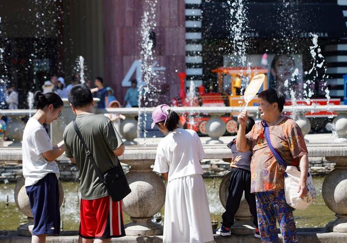 图为6月9日，市民在北京市朝阳区蓝色港湾商圈的喷泉池边感受凉意。新华社记者 陈钟昊 摄