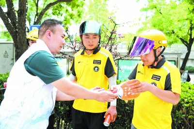     6月11日，北京市海淀区北太平庄街道总工会工作人员（左）为外卖配送员送上饮料及扇子。    新华社记者 任超/摄