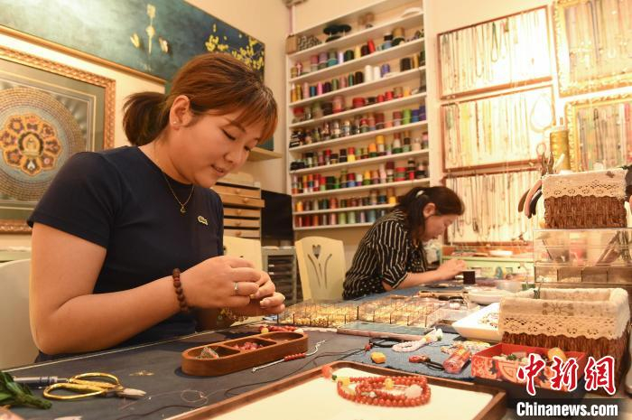 6月12日,在山东烟台一家饰品店,编织师傅忙着编织腕饰.曲正扬 摄