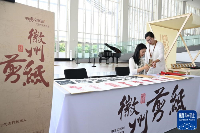 6月12日，观众正在展览现场体验徽州剪纸。新华社客户端发（张大岗摄）
