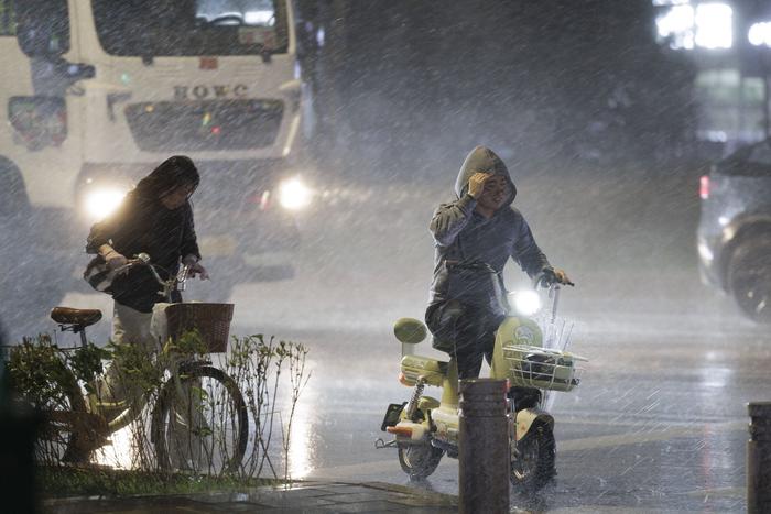 6月11日晚，北京市通州区通朝大街，阵雨、大风来袭，市民在雨中等待红绿灯。  新京报记者 王子诚 摄