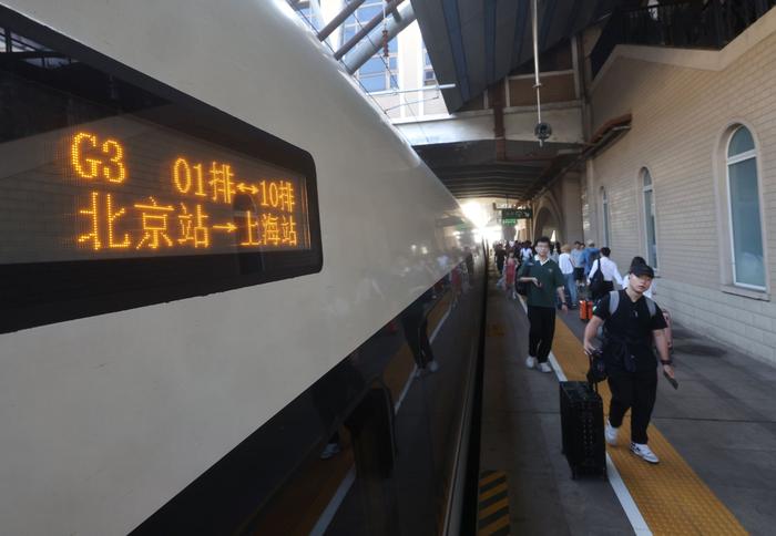 6月15日，北京站，京沪高铁G3次列车旅客拿着行李上车。  新京报记者 王贵彬 摄