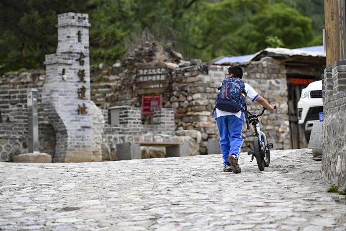 小朋友经过石峡村内的古堡遗址（5月31日摄）。新华社记者 陈钟昊 摄