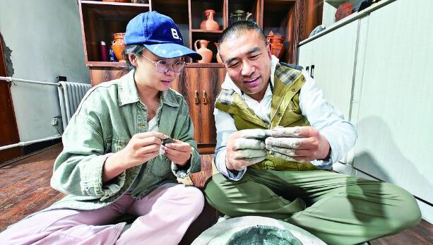 　　记者在东周（右）的指导下体验藏红陶制作。摄影：杨红霞