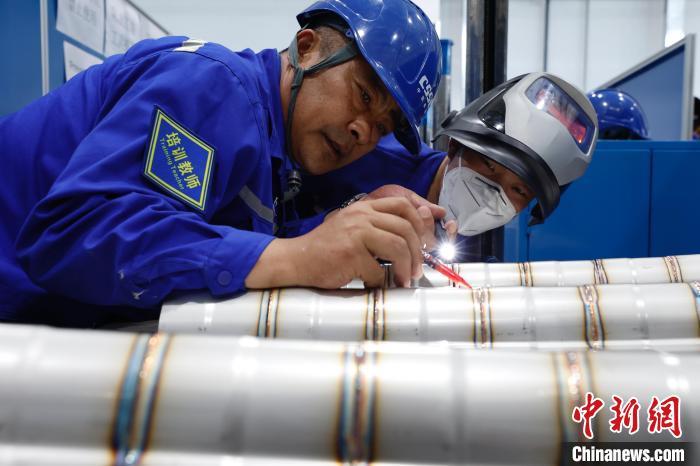 6月15日，手工焊接培训区域，培训教师正在检查学员的焊接板。　中新社记者 韩海丹 摄