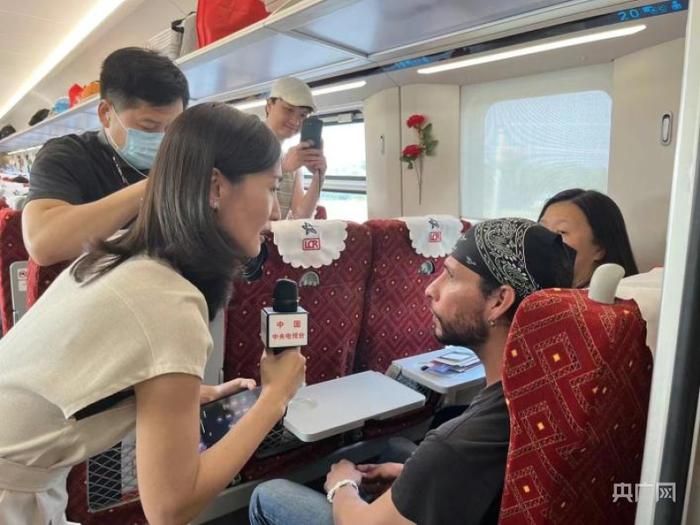 记者在中老铁路国际旅客列车上采访中外乘客