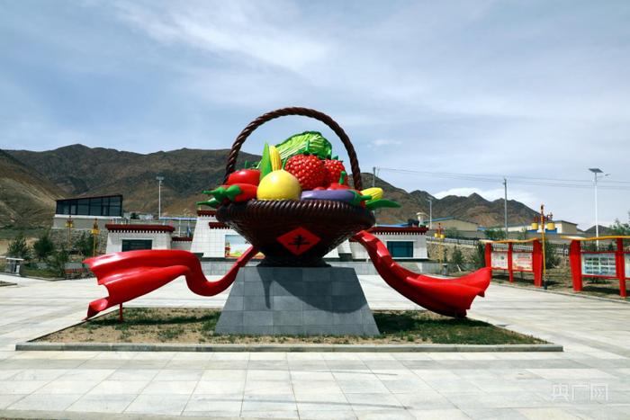 蔬菜篮雕塑立在阿亚村口（央广网记者 唐磊 摄）