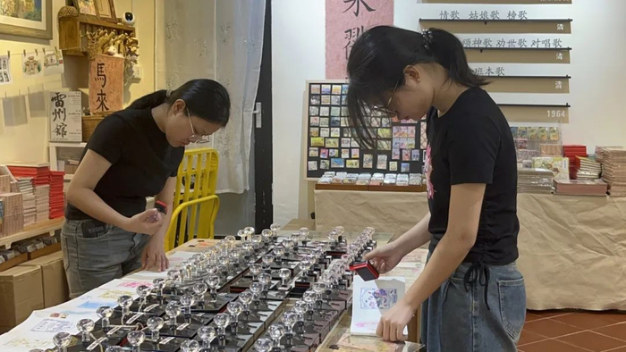 赤坎古商埠雷州馆里，工作人员为本子盖上印章。