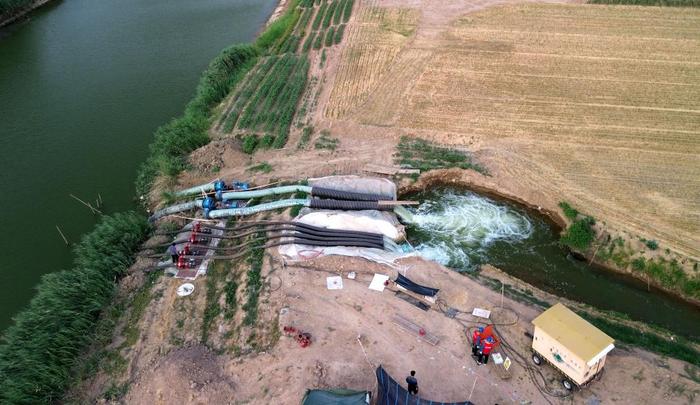 　　6月18日，在山东省巨野县麒麟镇的一处抗旱应急取水点，水泵正在抽水输入农田灌溉渠道（无人机照片）。新华社记者 徐速绘 摄