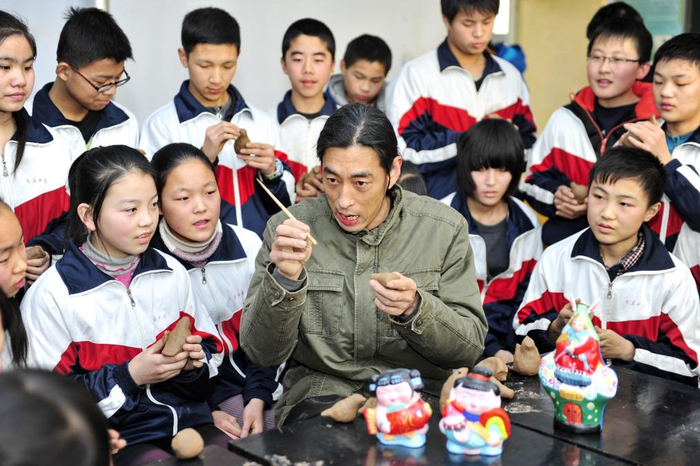 2015年1月9日，在河北省泊头市文庙中学，“三痴斋”泥塑传承人宋长峰（前中）在教学生们制作鸟哨。