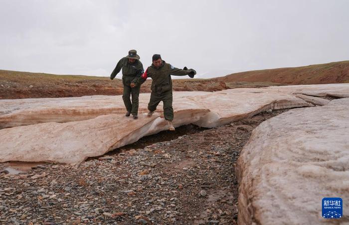 6月15日，羌塘国家级自然保护区野生动物专业管护队员索朗（左）和罗布检查河面冰冻情况。新华社记者 晋美多吉 摄