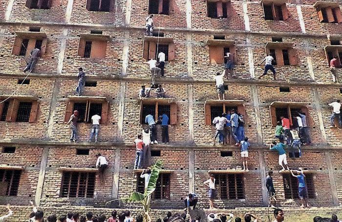 ▲2015年，印度一处学校十年级升学考试考场外，家长翻墙帮学生作弊