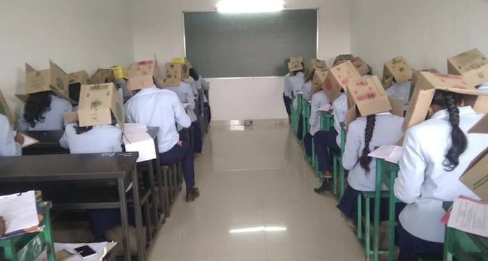 ▲为防止学生作弊，印度一学校让学生头戴纸盒考试