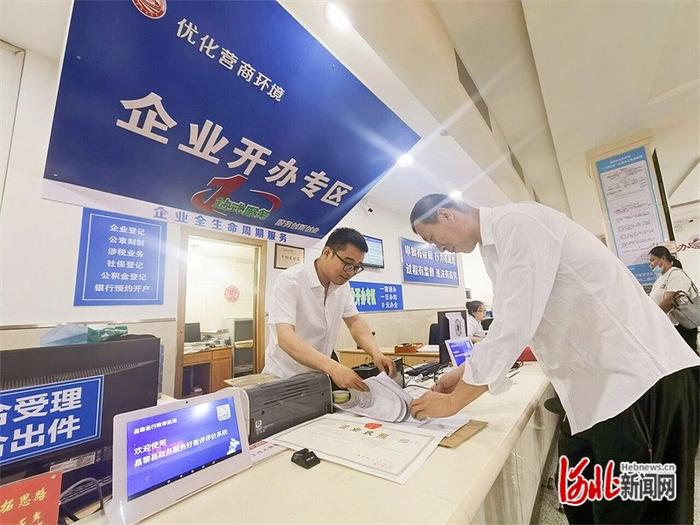 6月18日，张乔博（右）在昌黎县数据和政务服务局企业开办专区办理企业迁址手续。河北日报记者 孙也达摄