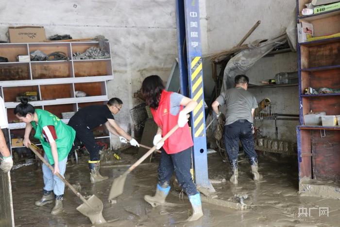 在镇远县羊坪镇，干部群众正在帮商户清除店内的淤泥（央广网发 尚丹 摄）