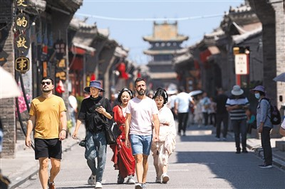游客漫步在山西晋中平遥古城的街道上，体验特色旅拍。新华社记者 詹彦摄
