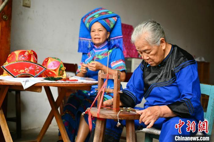 7月2日，广西靖西市新靖镇旧州村，居民黄肖琴(右)和她的儿媳赵金玉在制作绣球。　俞靖 摄