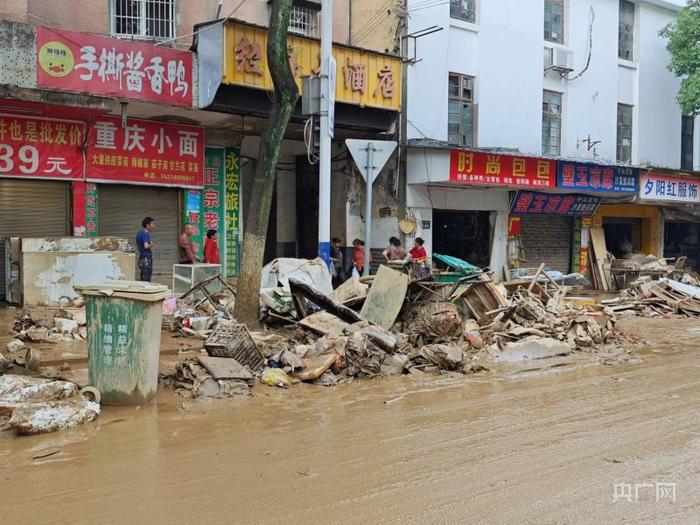 汉昌街道民建路积水已退，路上布满淤泥，垃圾堆在道路两侧（央广网记者杨清 摄）