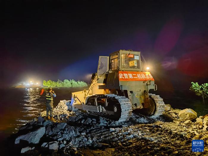   7月7日凌晨，在湖南省岳阳市华容县团洲垸洞庭湖一线堤防决口处，武警部队官兵操纵工程机械封堵决口。新华社记者 李秉宣 摄